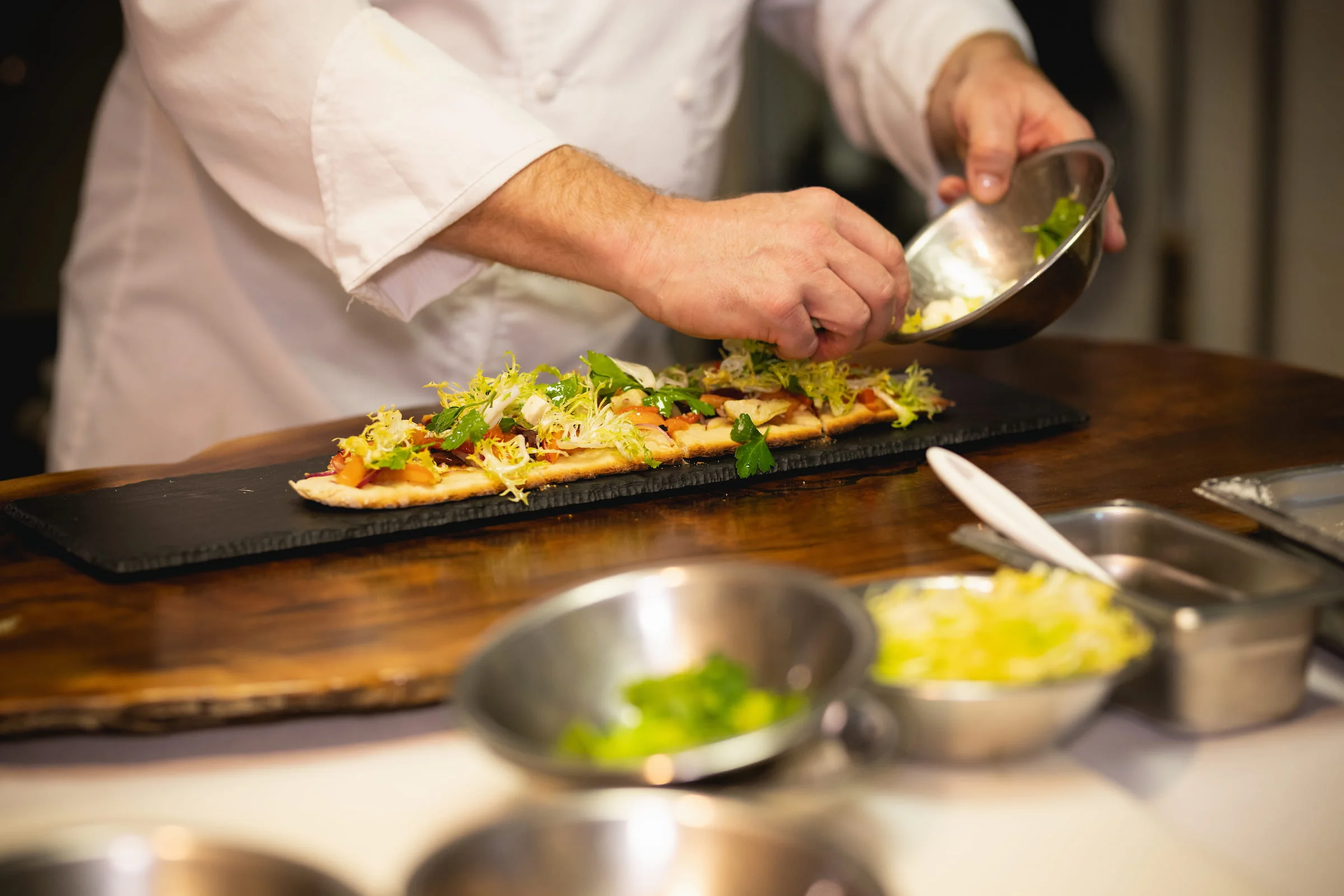 Chef garnishing a plated dish in the kitchen