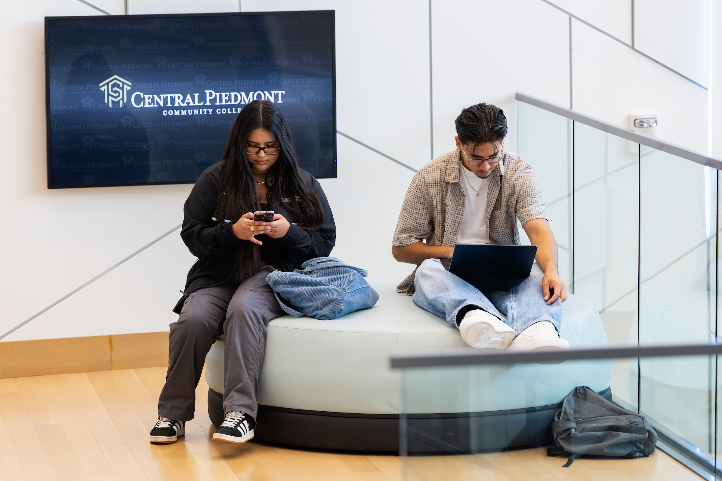 Two Central Piedmont students working on their devices on campus