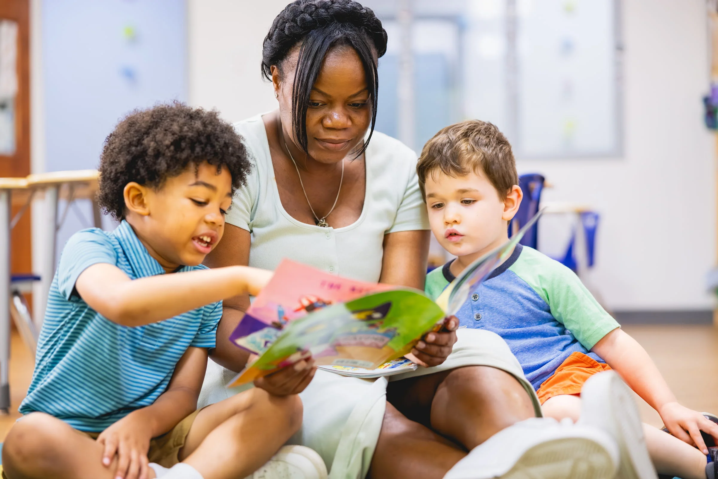 Adult reading a picture book with two young children