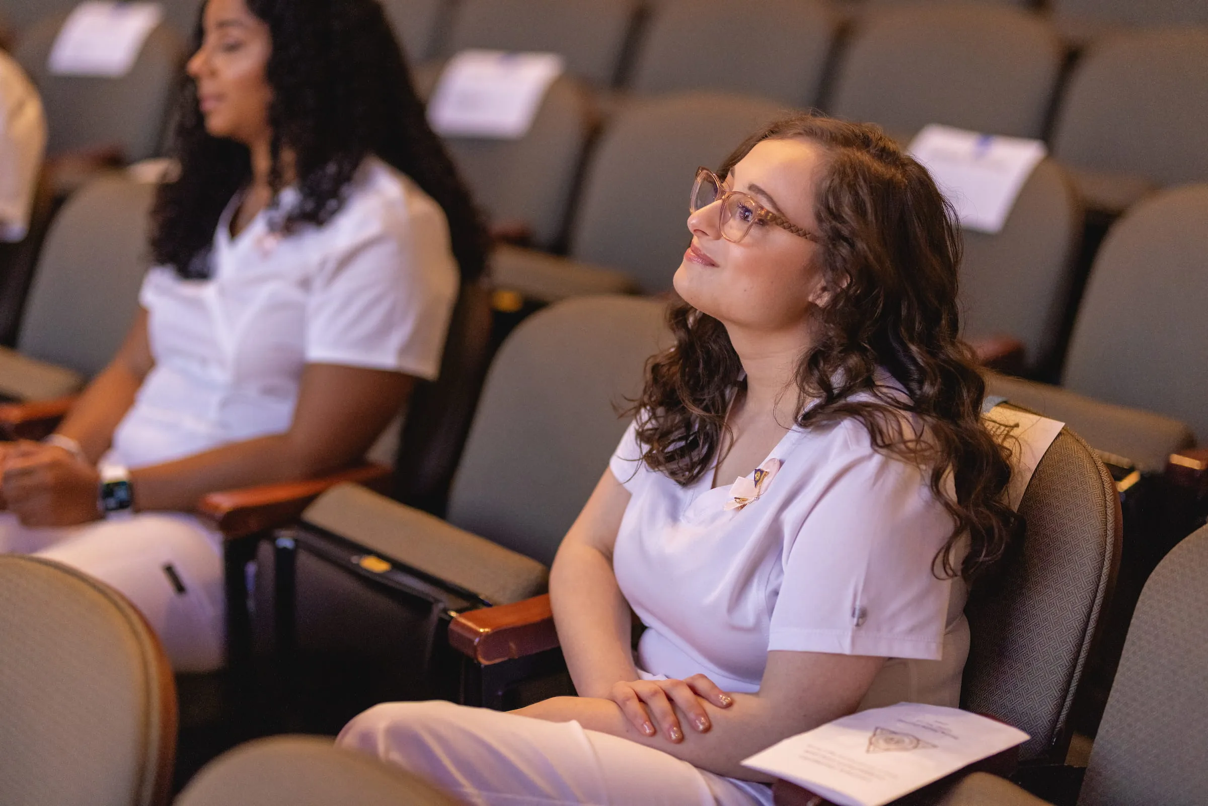Nursing students in scrubs listening during a lecture