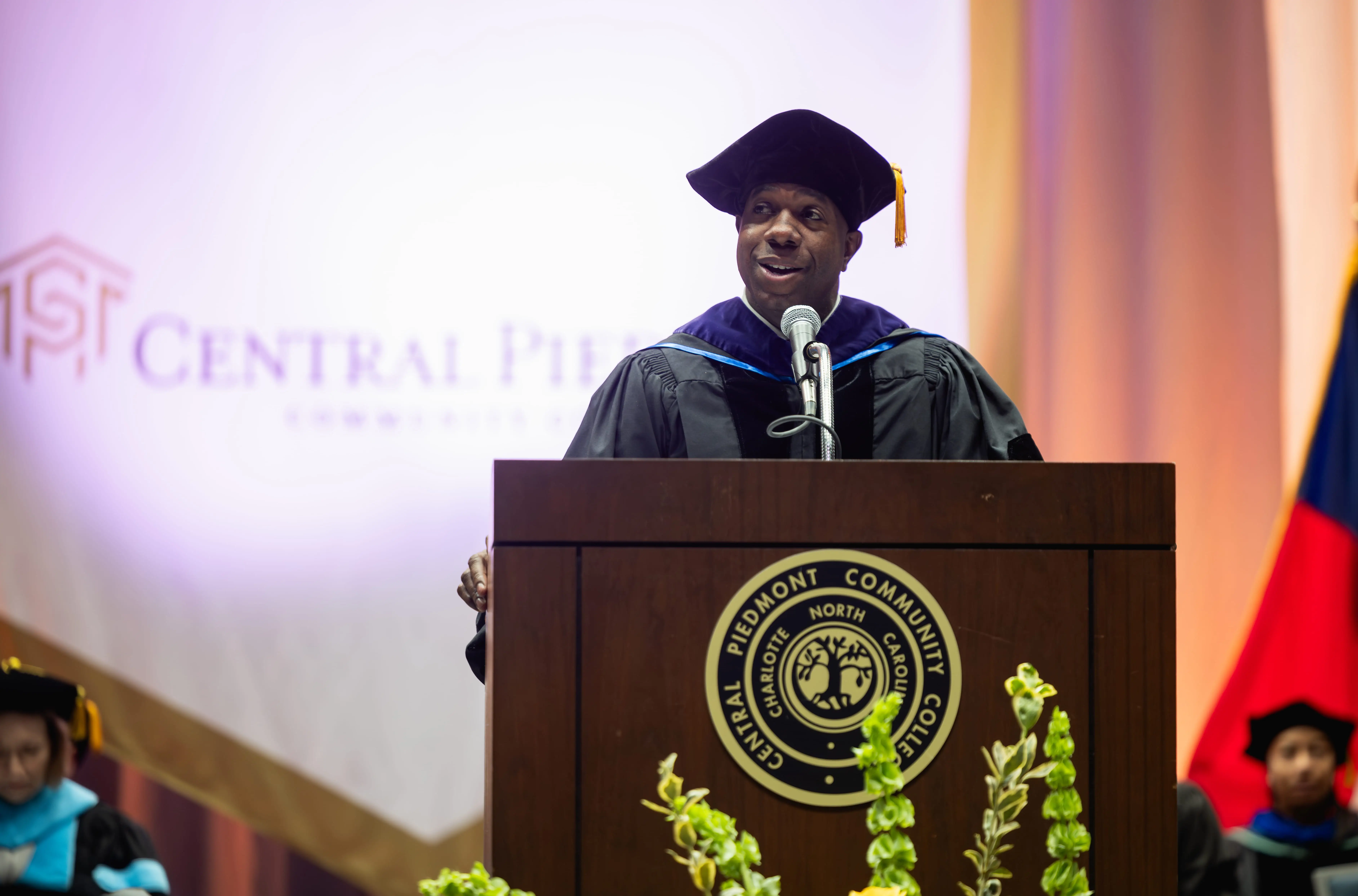 Speaker in academic regalia addressing the audience at commencement