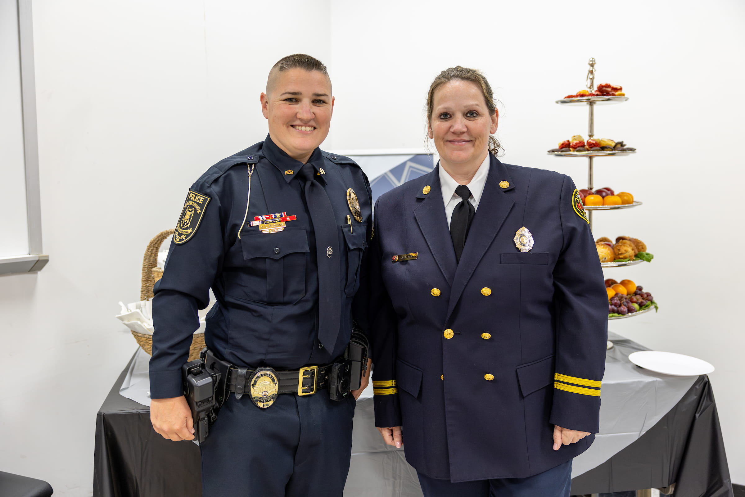 A police officer and a fire officer in dress uniform at a public safety reception