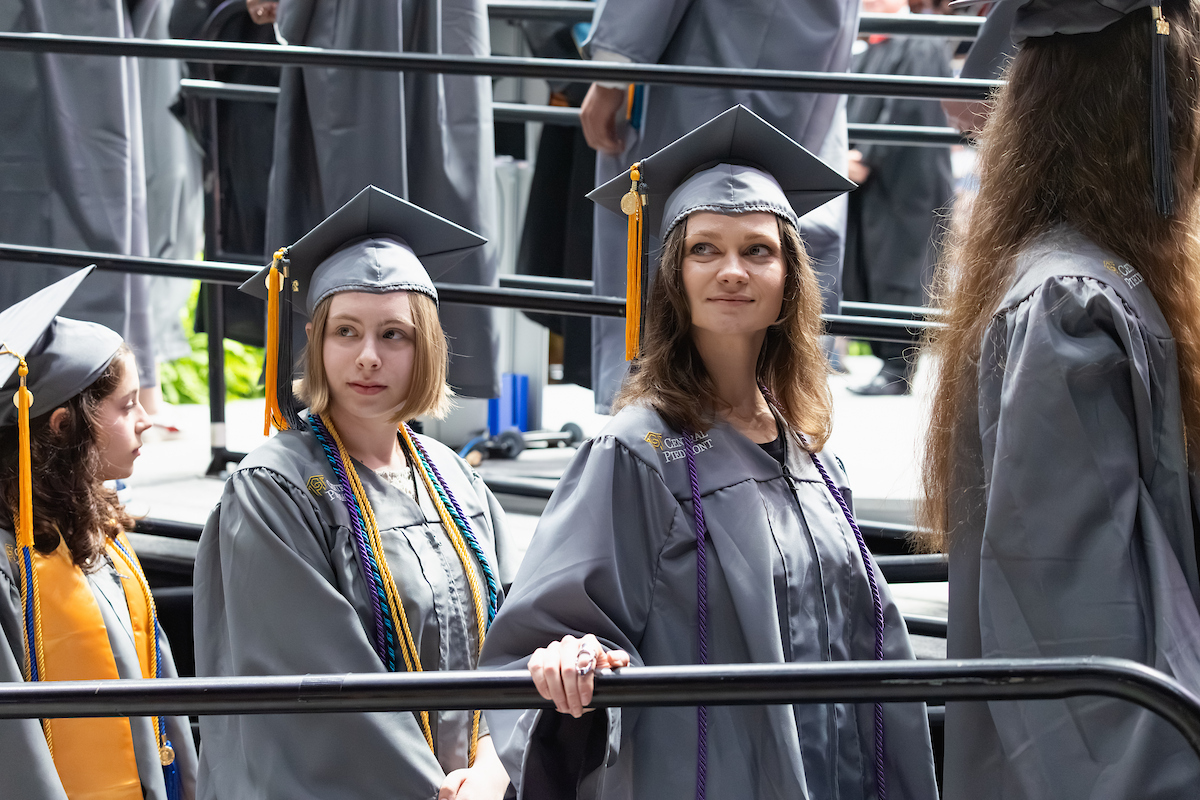 Student staring into the distance while ascending the steps to the graduation stage, wearing a cap and gown