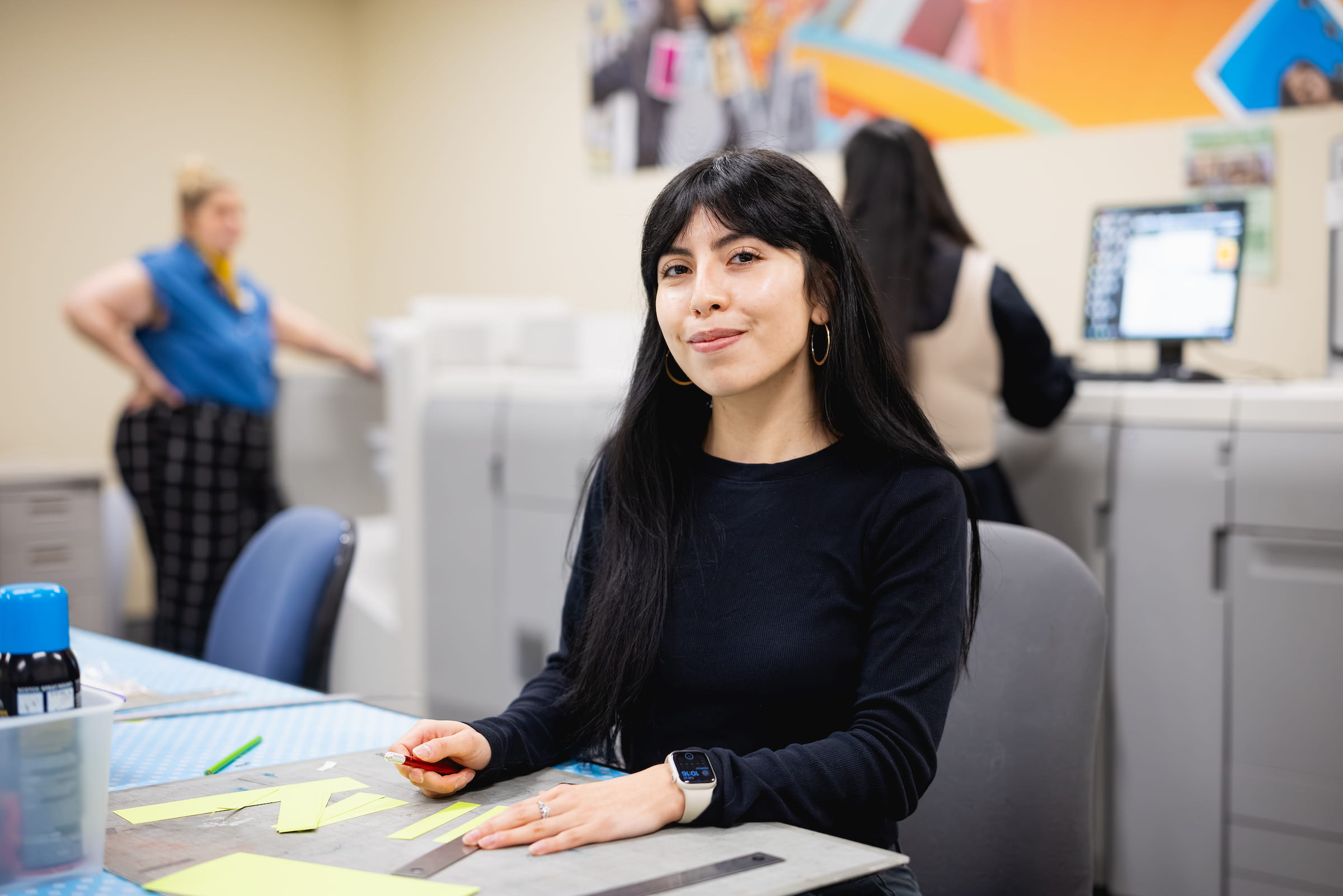 Graphic design student at a workstation in a studio with a colourful mural