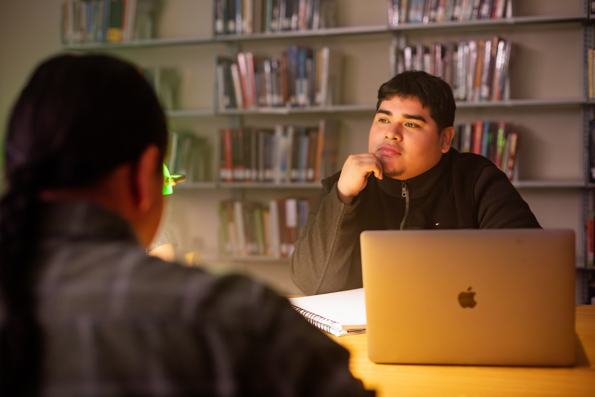 Student staring off into the distance in front of an open laptop