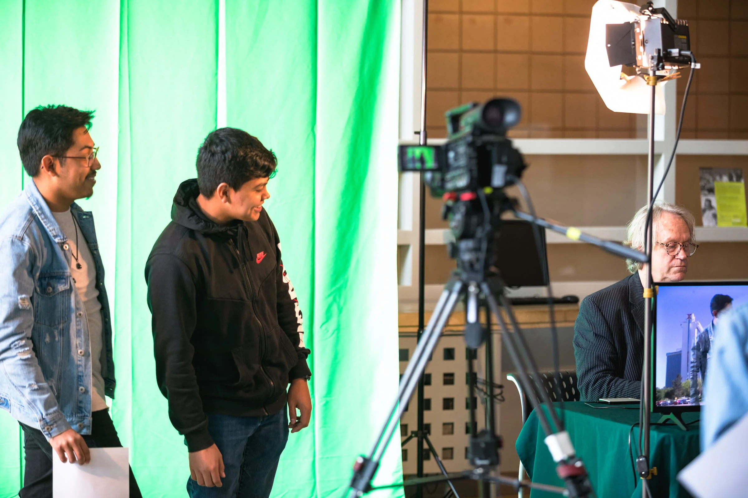 Students filming in front of a green screen with a studio camera and lighting