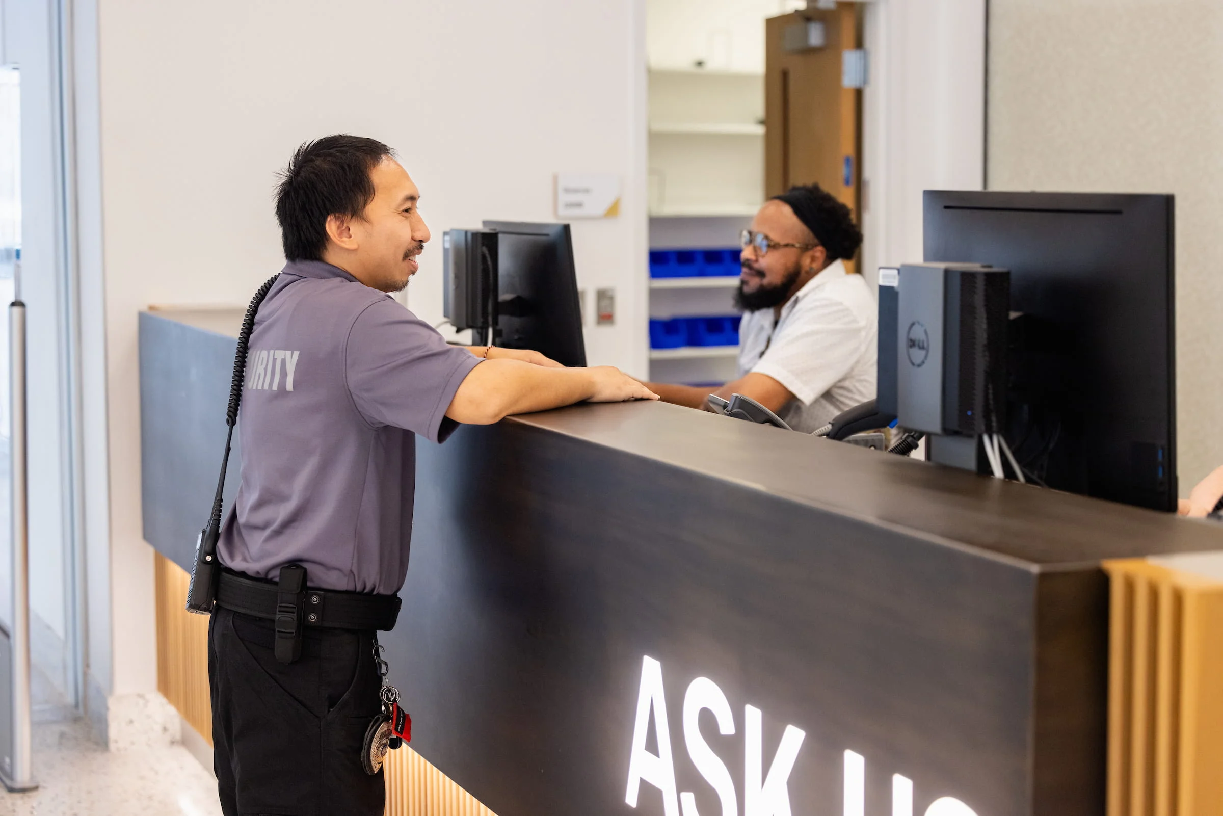 Campus security officer talking with staff at the Ask Us desk