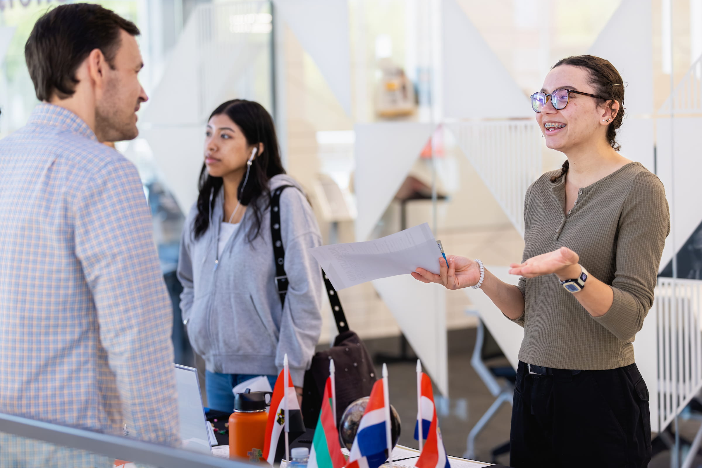 Central Piedmont student chatting with faculty member about international studies with countries’ flags in foreground.