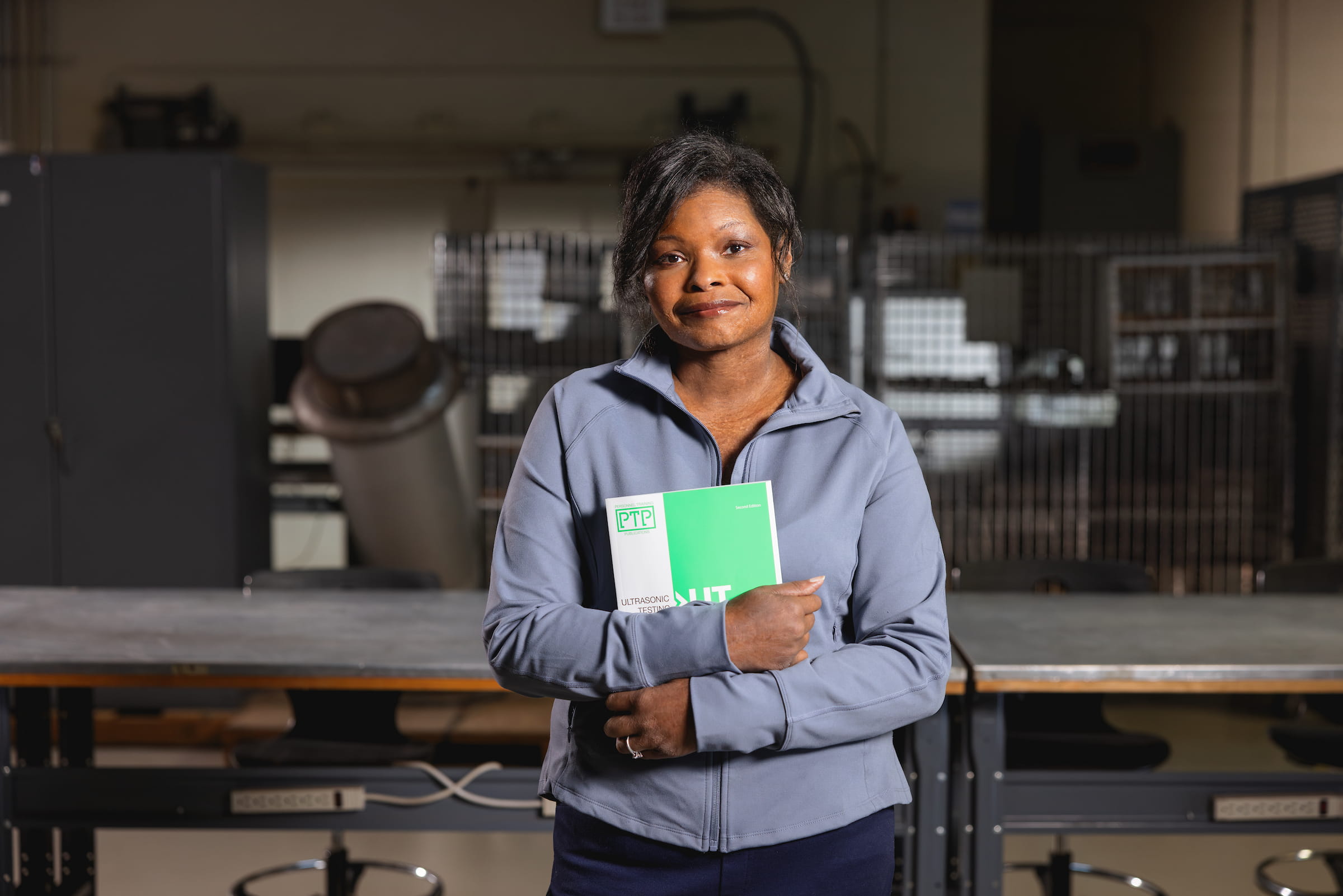 Nondestructive examination technology student holding a manual in a testing workshop