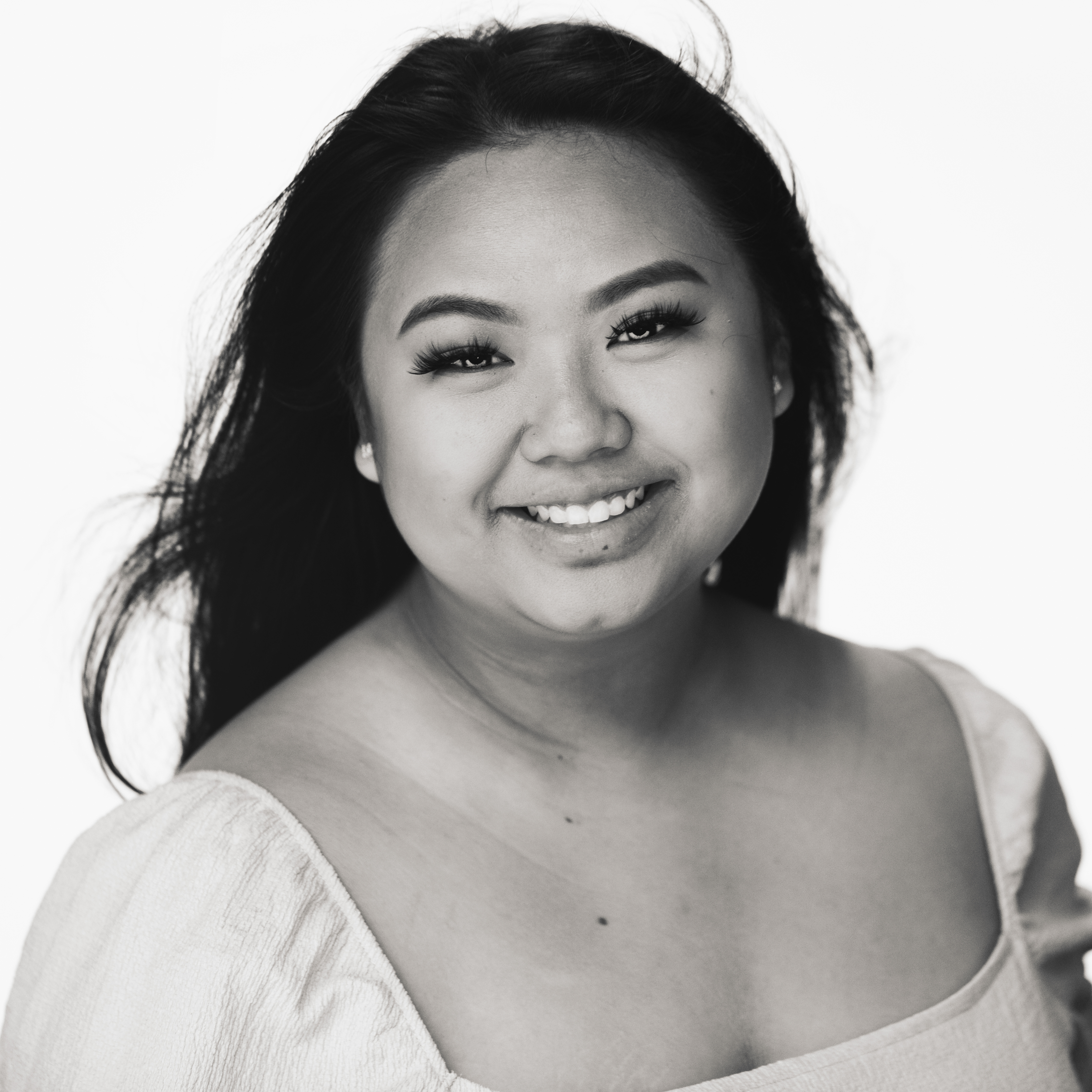 Black and white headshot of Amanda Vang in a cream colored, square neck top with hair blowing in the breeze