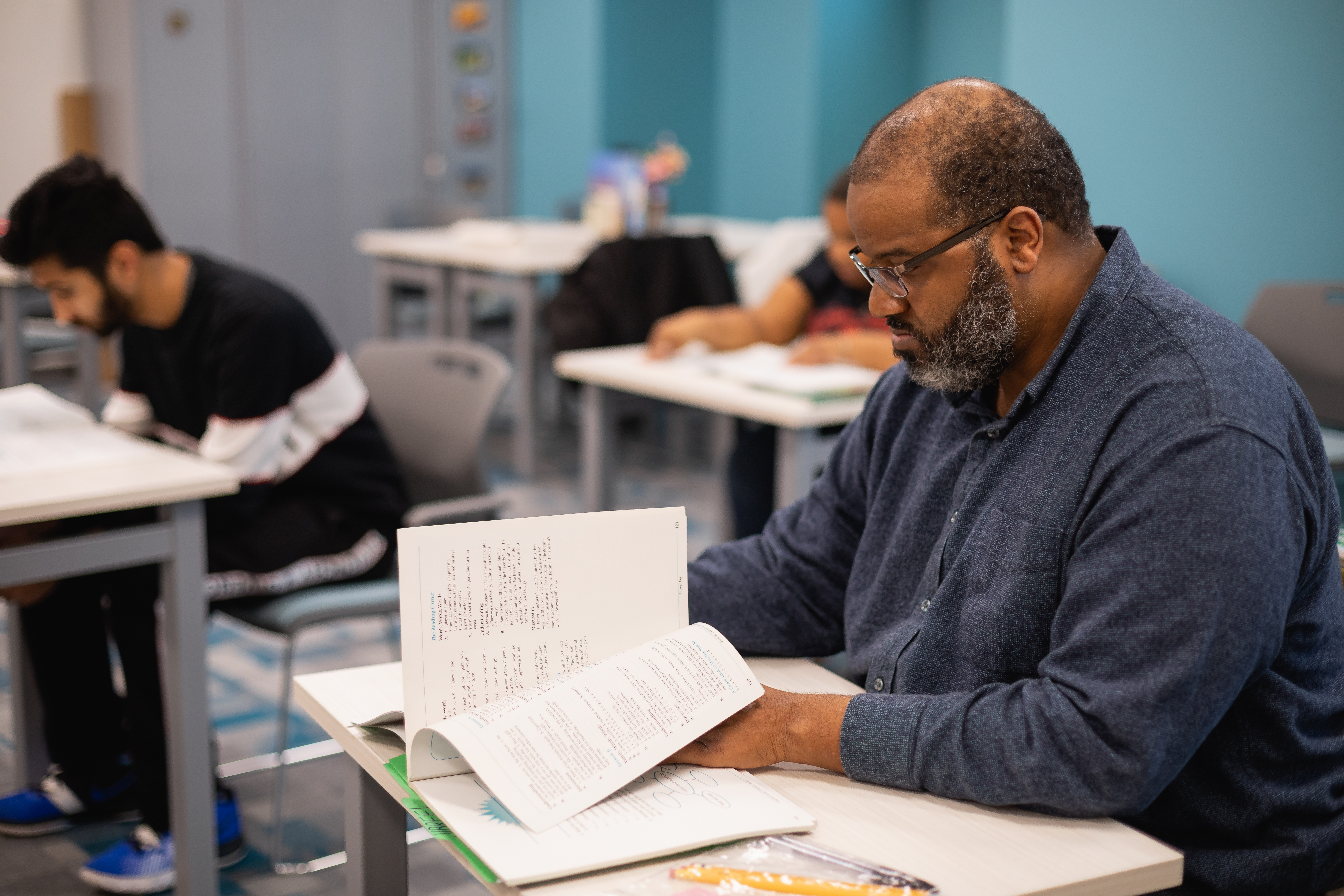Adult student in a desk with a book