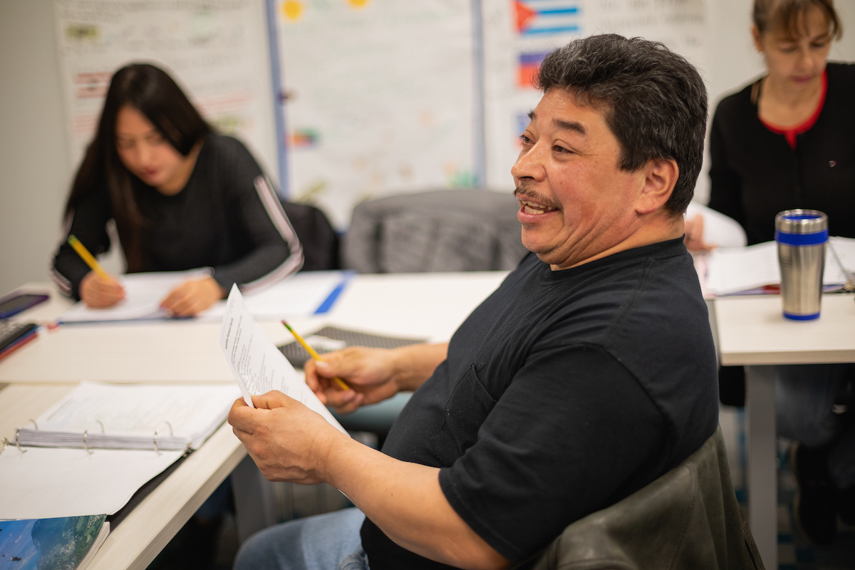 Adult student in an Integrated Education Training classroom, holding a piece of paper and smiling