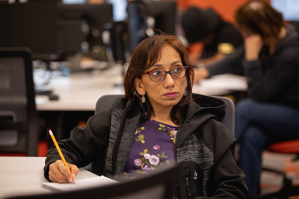 Adult learner sitting in an Integrated Education Training classroom, prepared to write with a pencil.