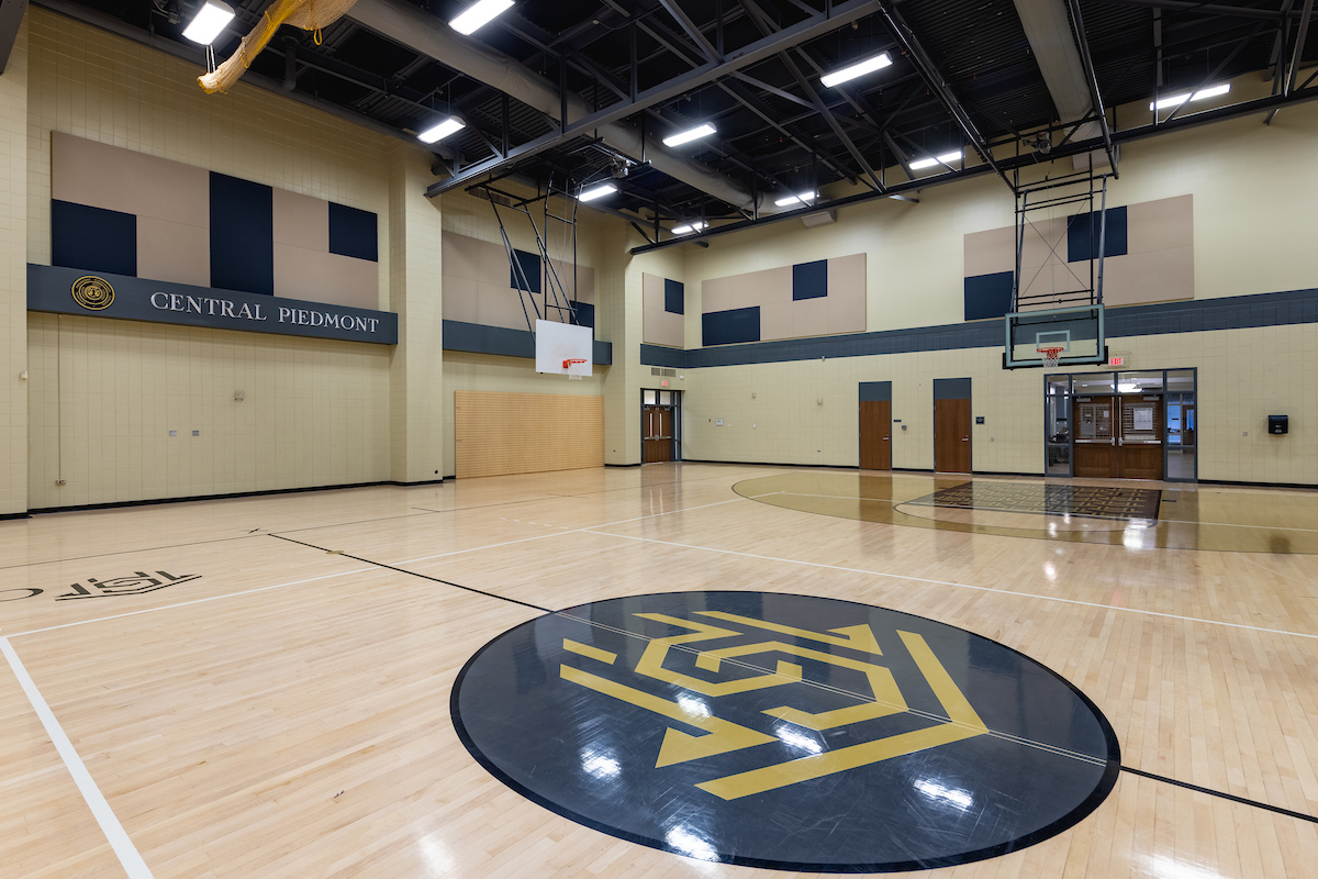 Empty Worrell Gymnasium with basketball courts and Central Piedmont logo at halfcourt.