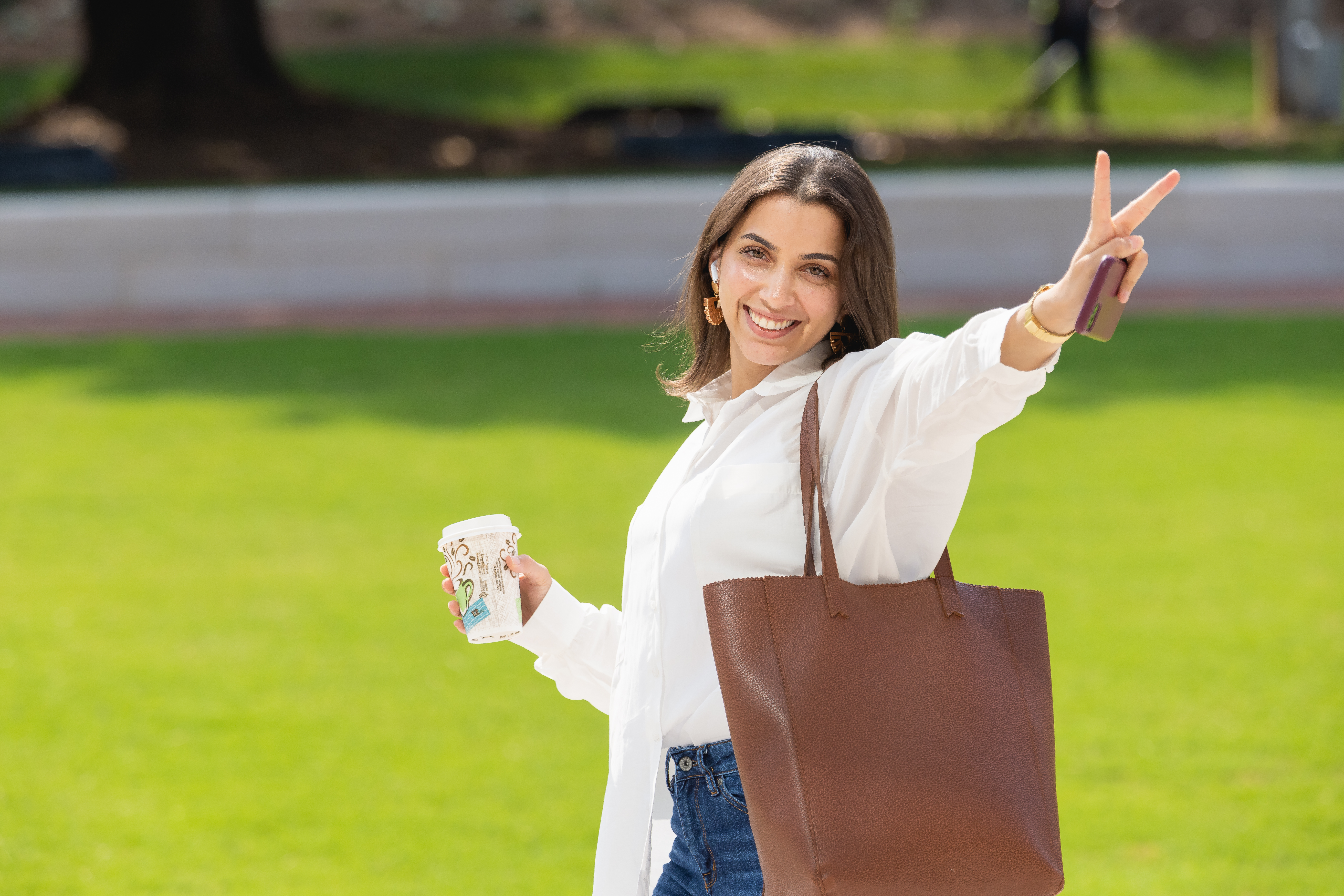 Student with coffee giving peace sign