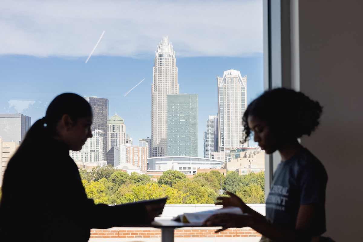 Silhouette of two people sitting at a table with the Charlotte skyline in the background