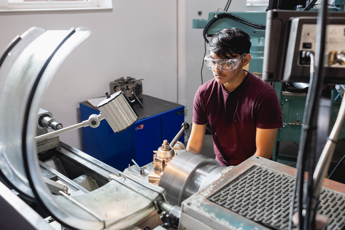 Student tinkering in an engineering lab and wearing safety goggles