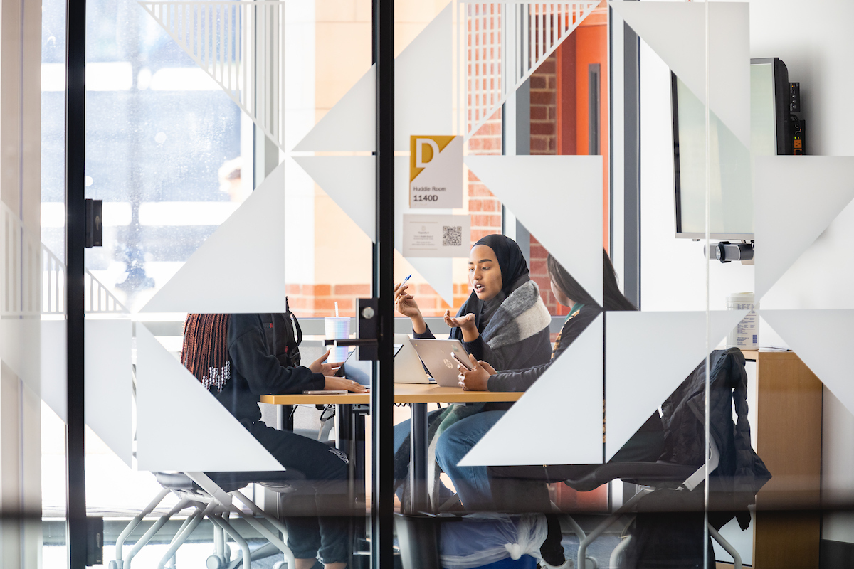 Students seated around a table in a study room at the library