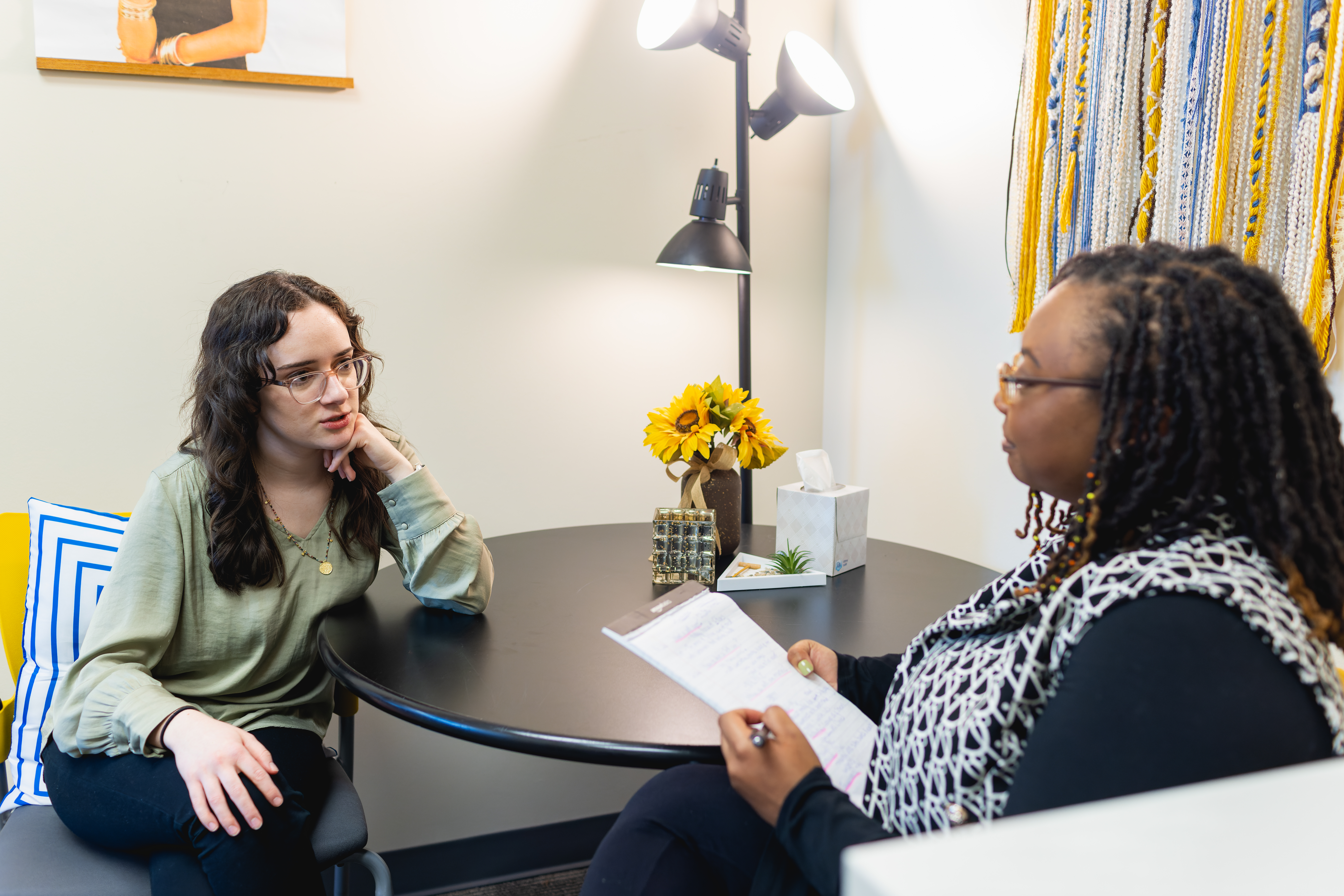 Central Piedmont student chatting with advisor while both sit at small circular table in office.