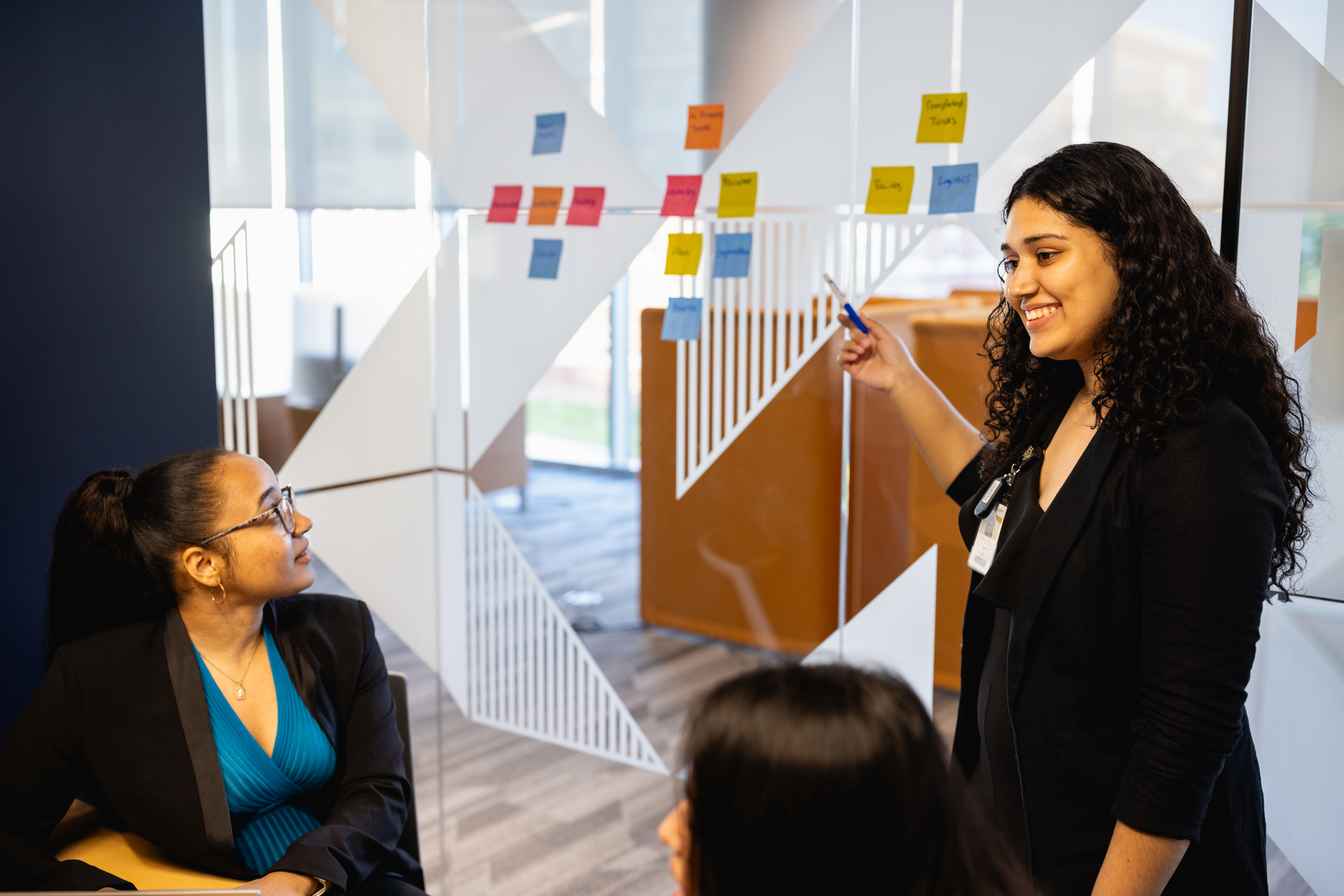 Students collaborating by placing sticky notes on a glass wall