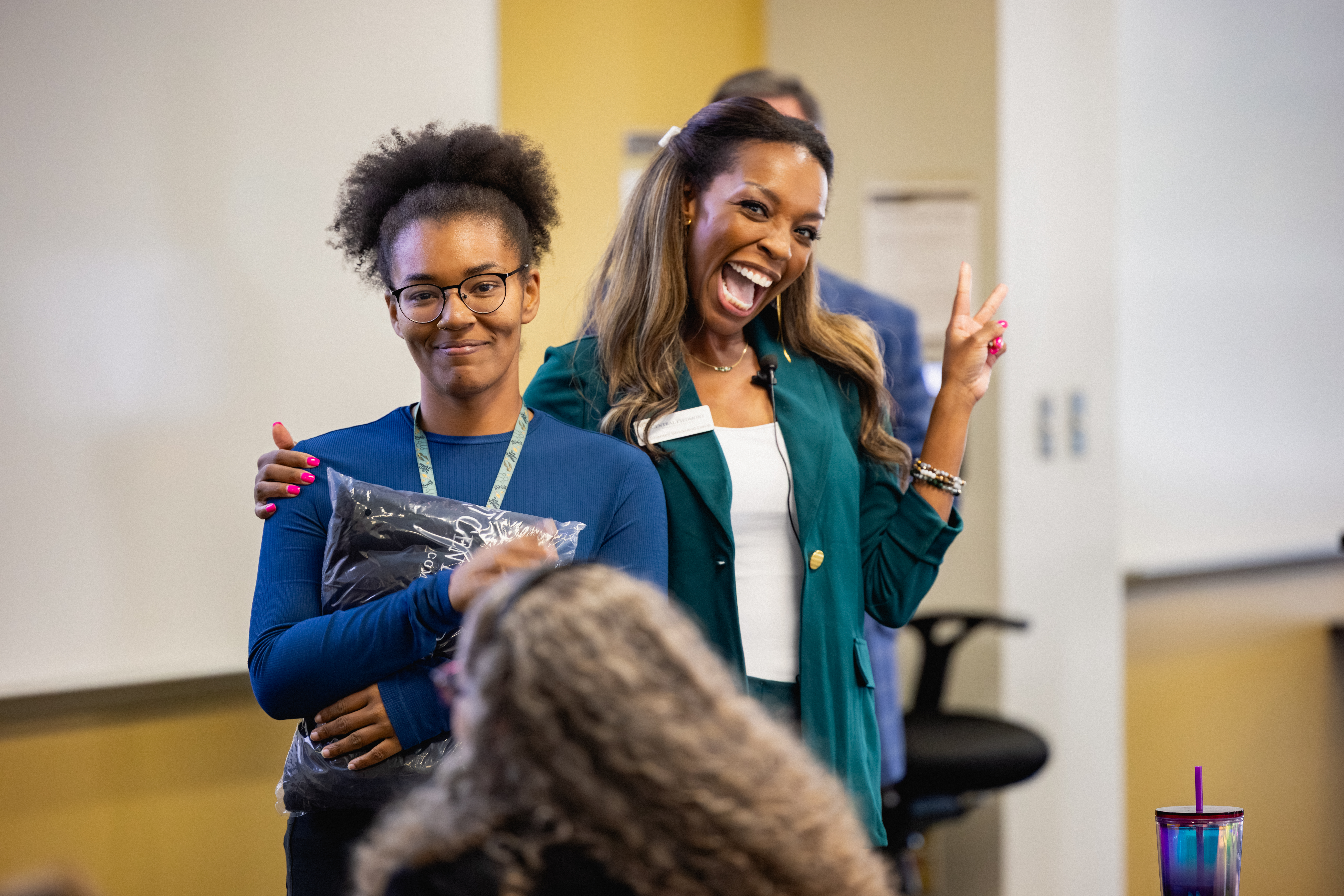 Staff member with arm around student and wide smile
