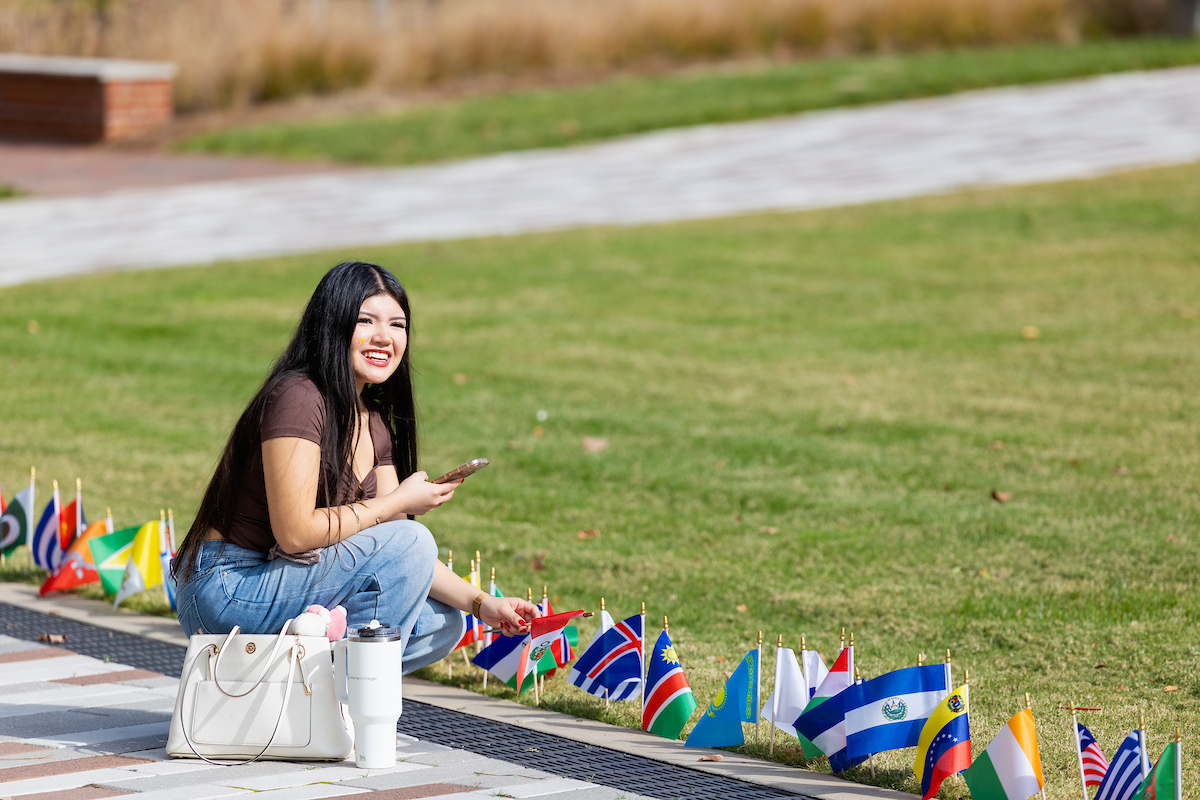 Student crouching to examine a flag planted on the student quad