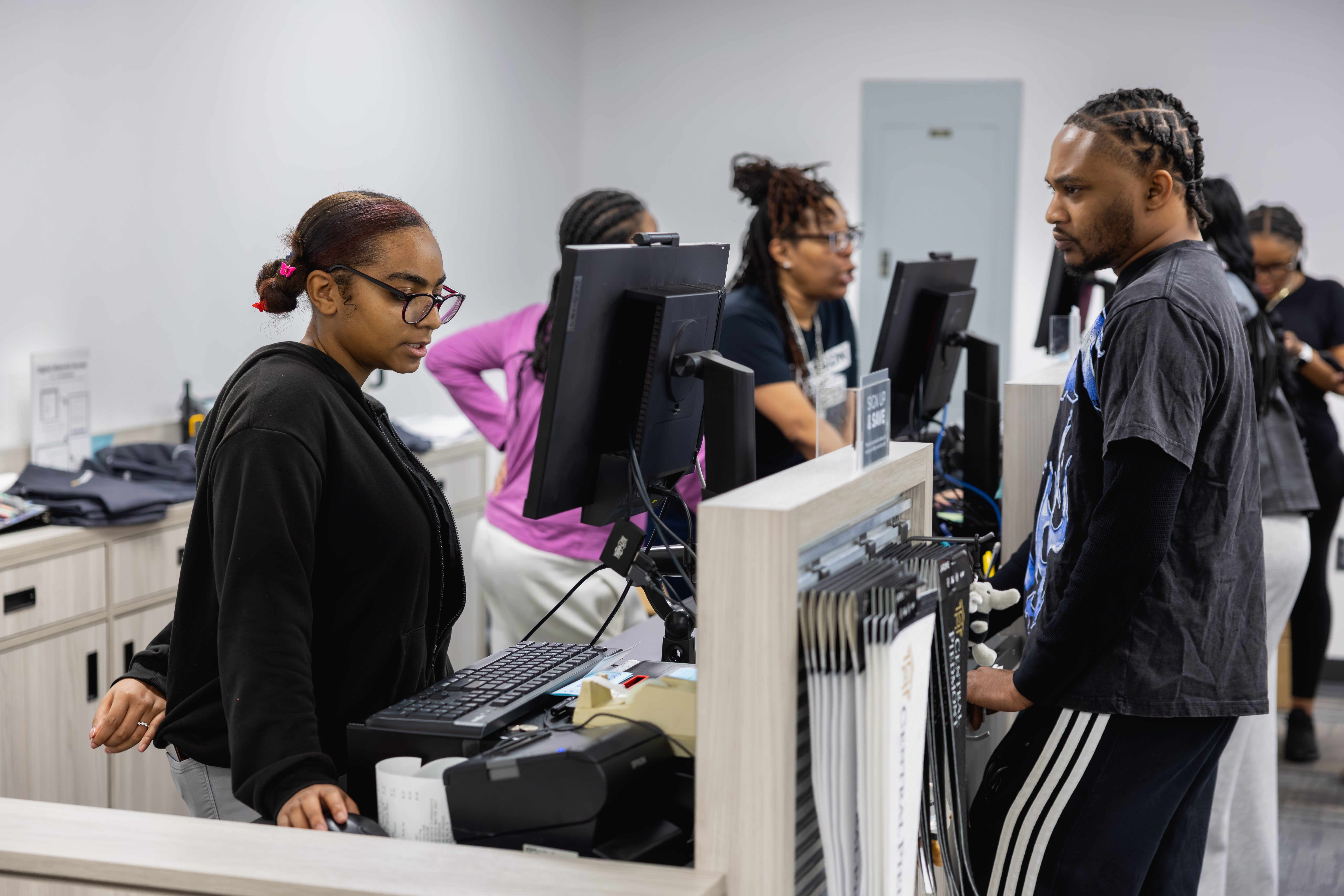 Student at campus store checkout counter with worker behind the desk