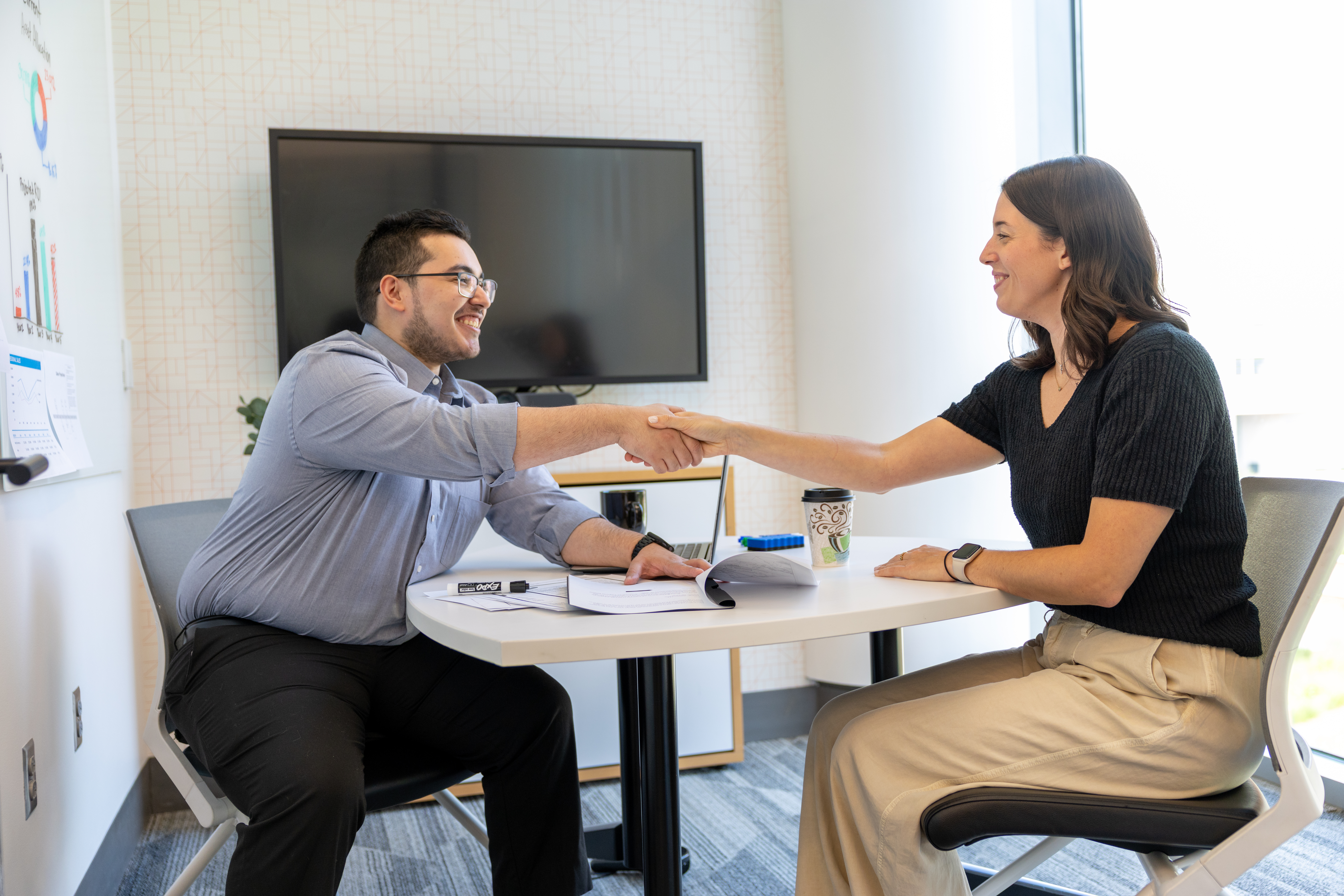 People shaking hands across a desk