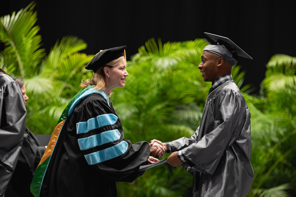 Student and faculty member shaking hands during graduation