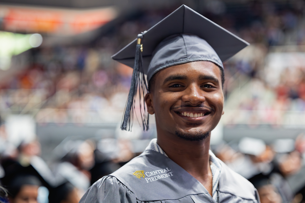 Central Piedmont student posing for a headshot at graduation, wearing cap and gown