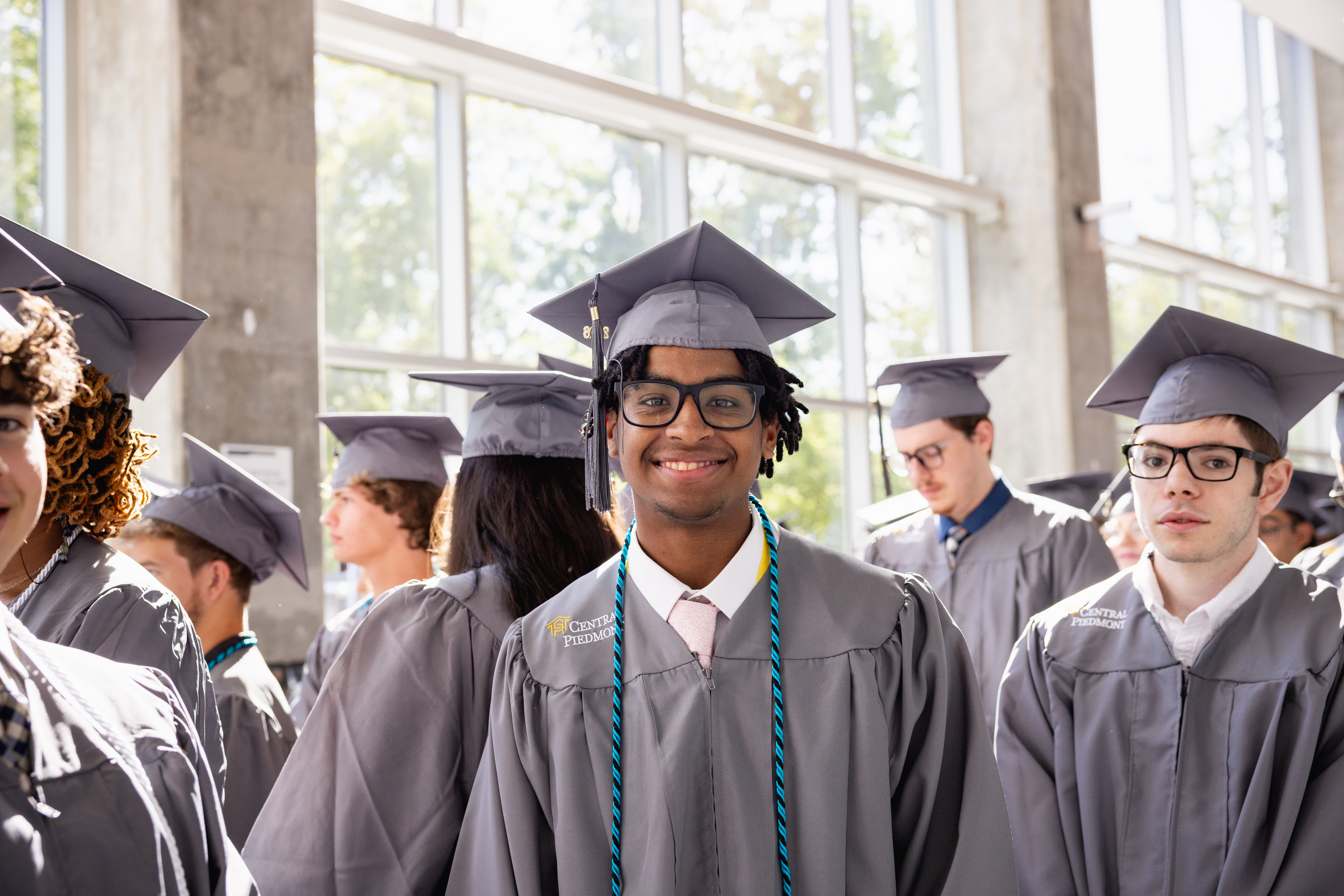 Multiple students wearing caps and gowns gathering in the hallway ready to walk into the commencement ceremony