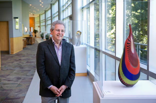 Bill Gorelick standing beside a large multicoloured glass sculpture