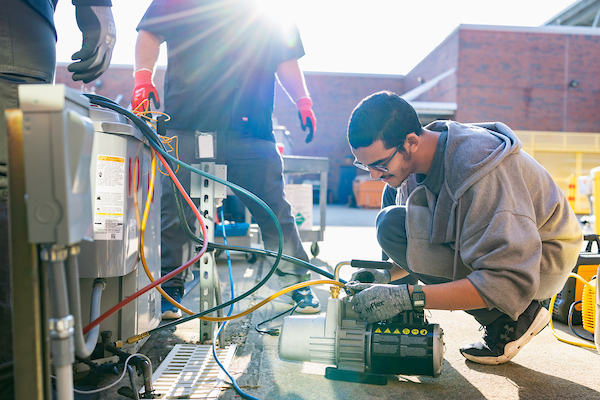 Student crouching to tinker with HVAC wires