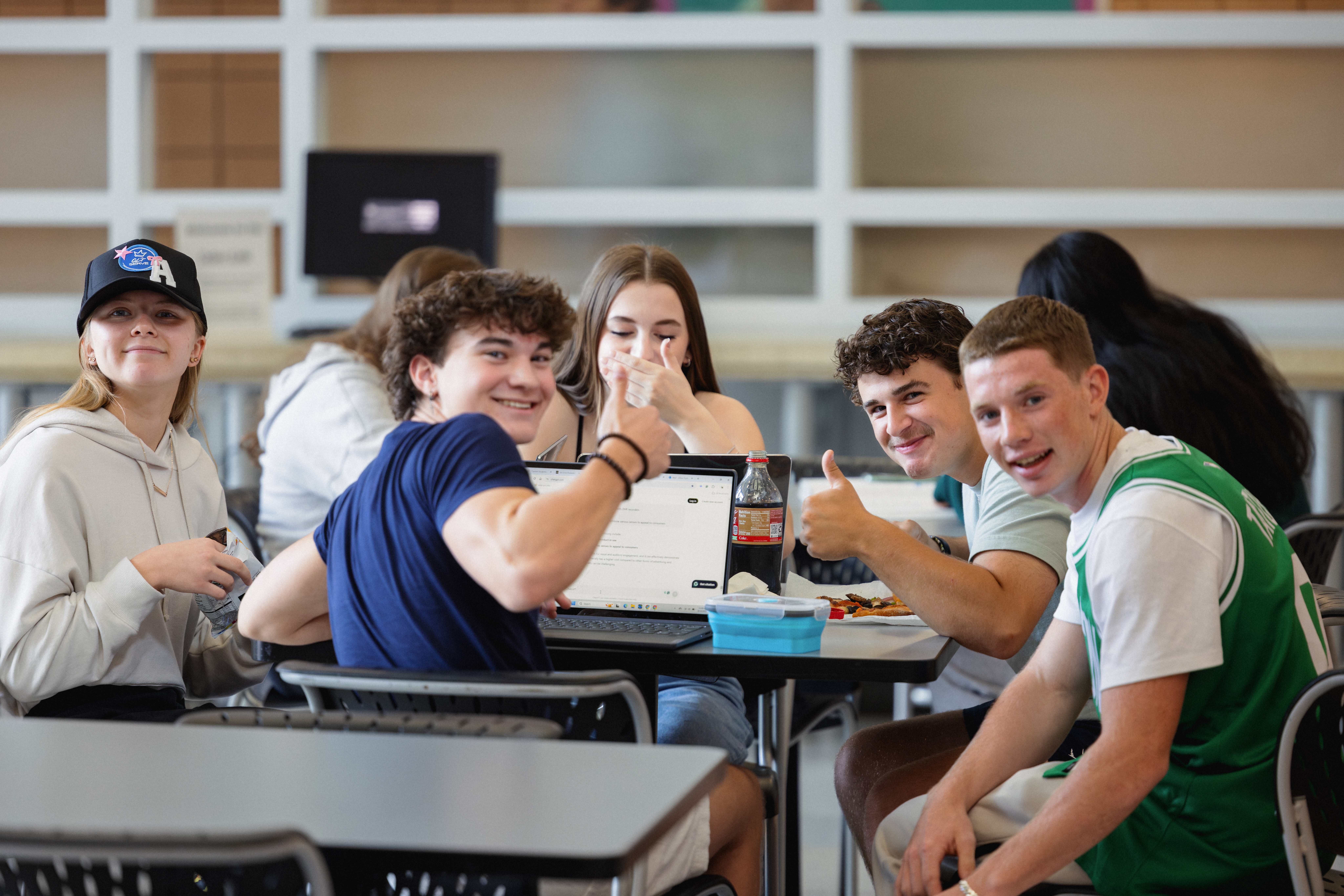 Young students at a table giving thumbs up
