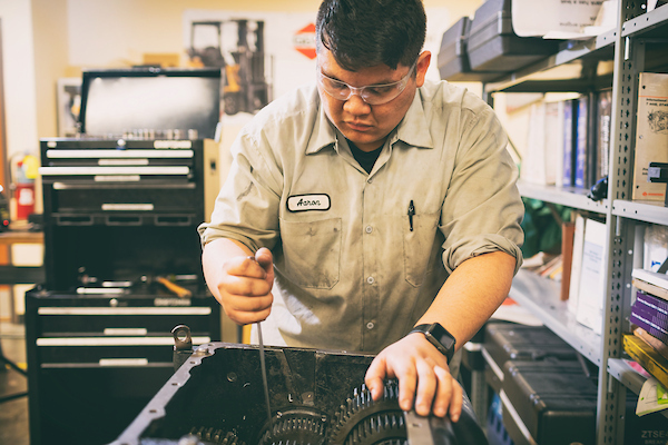 Automotive systems technology graduate repairing heavy equipment