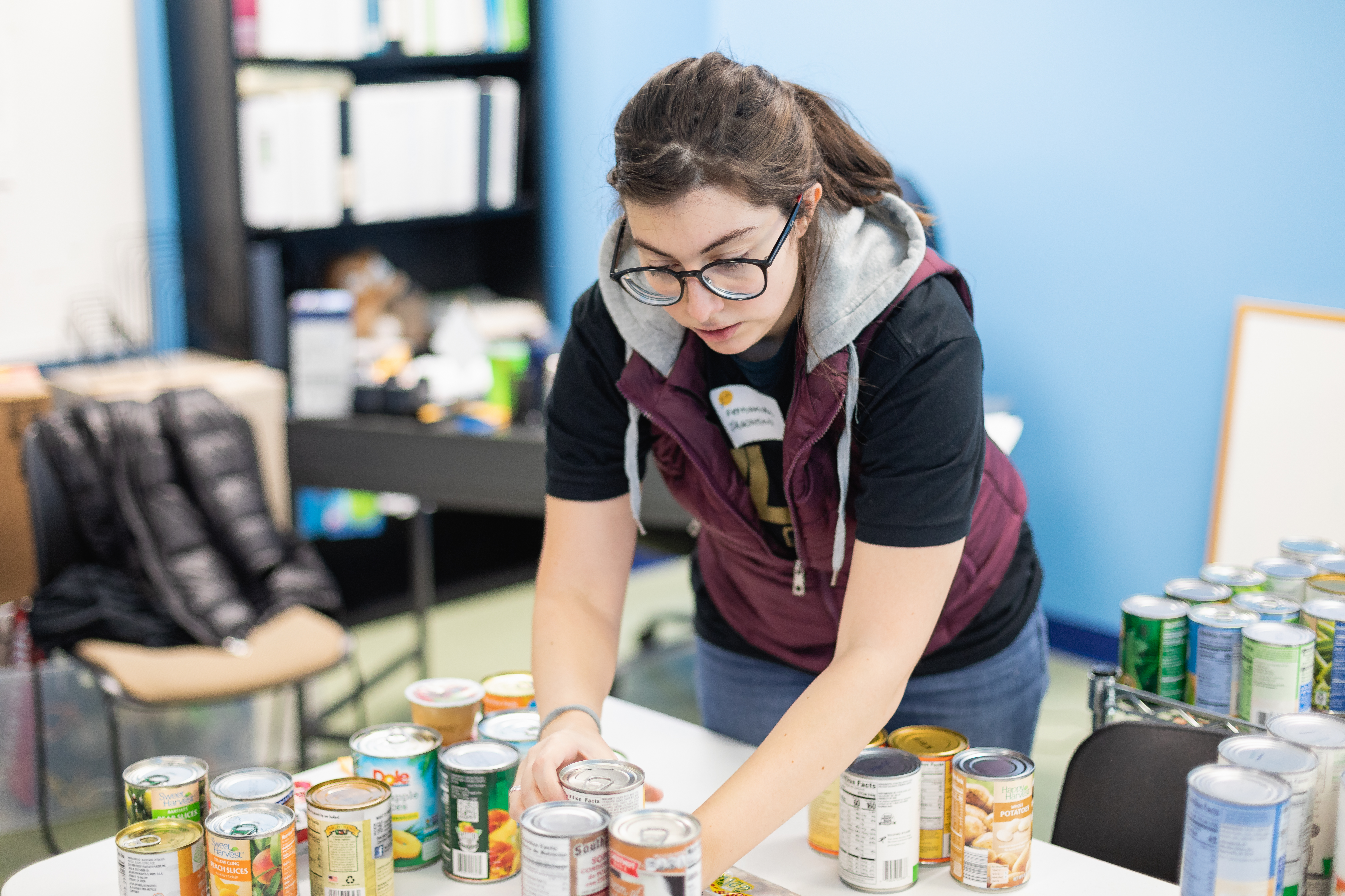 Student leaning over a table organizing canned foods