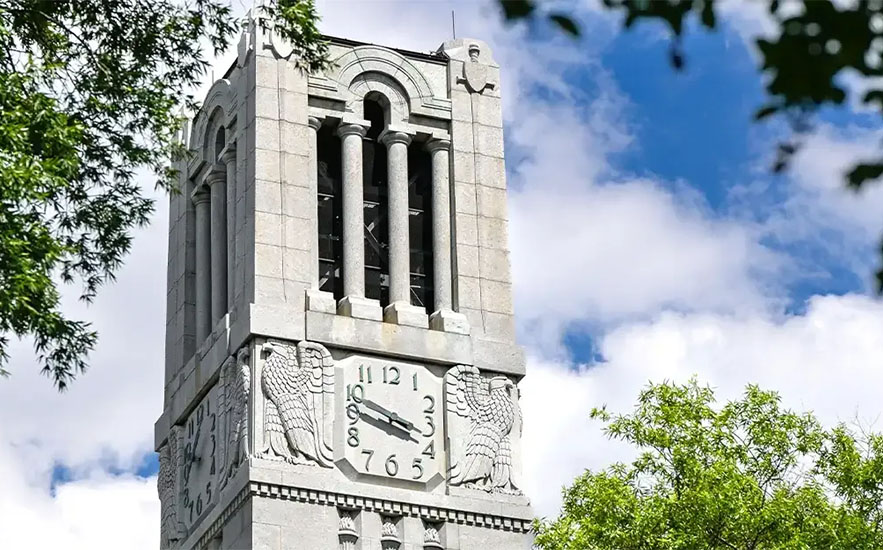 The NC State University bell tower against a cloudy sky