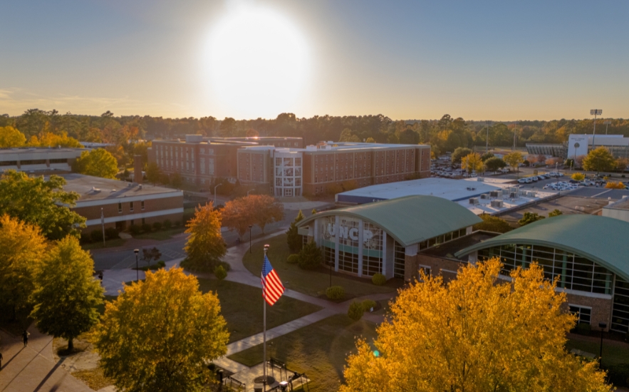 Aerial view of the UNC Pembroke campus at sunset with autumn trees