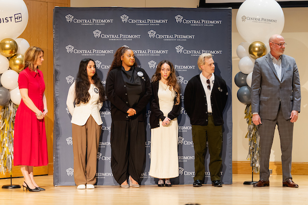 Honors program students standing on stage in front of a Central Piedmont Community College backdrop