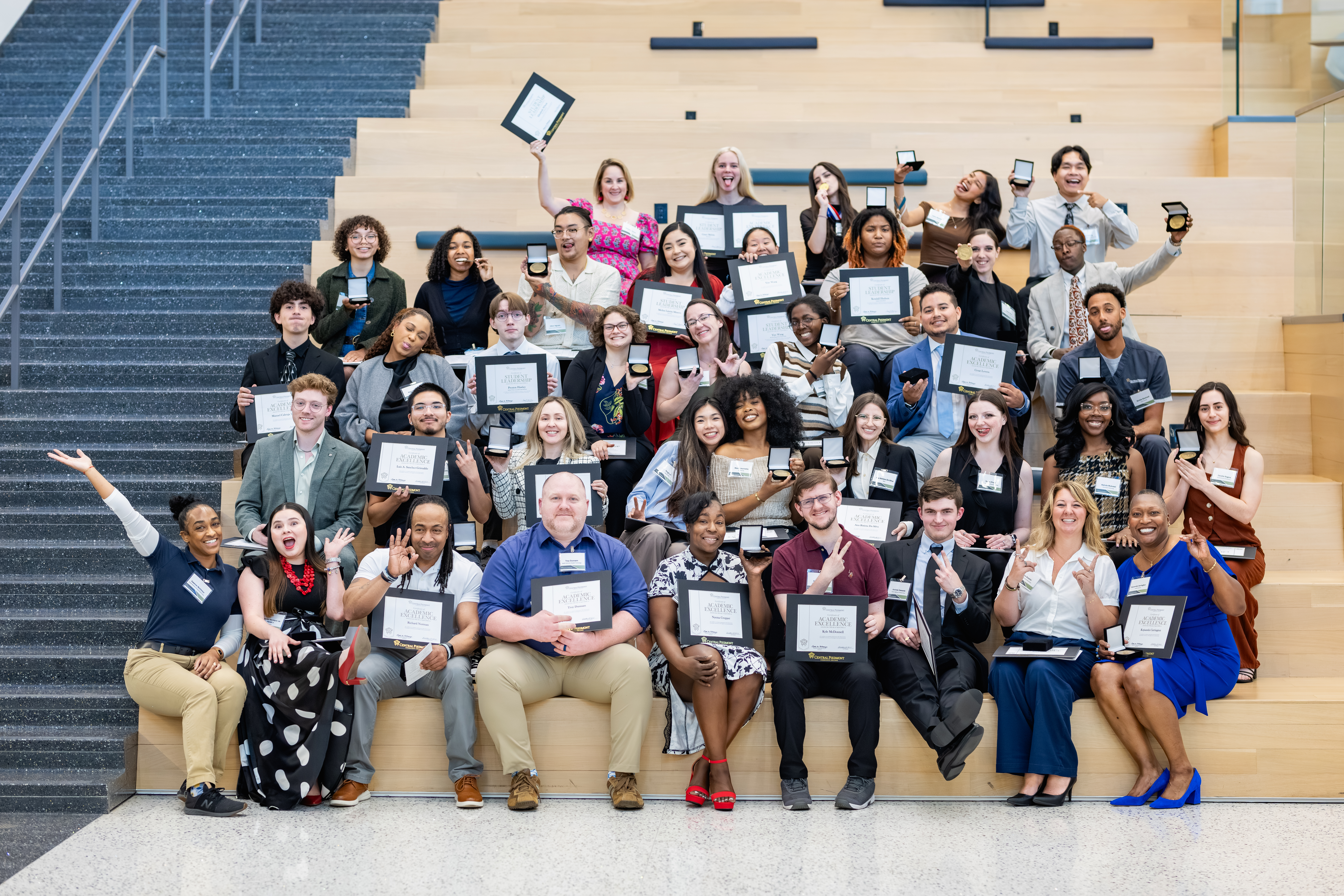 Very large group of Central Piedmont students posing on stairs of the Parr Center holding academic excellence awards.