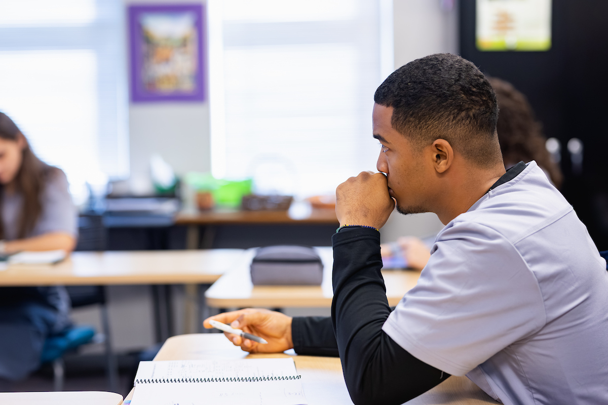 Cytotechnology student with an open book, taking notes in class.