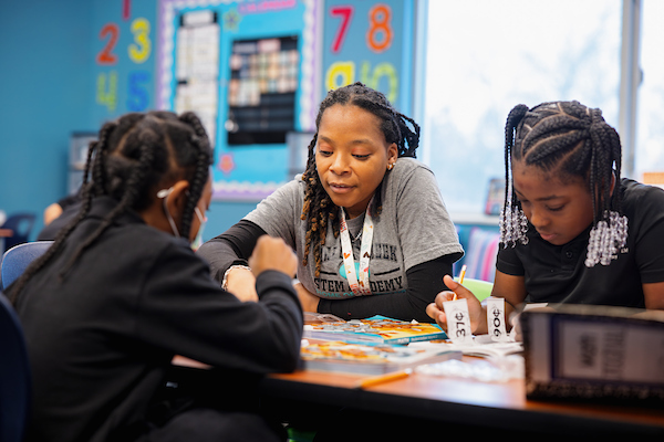 Student teacher sitting at a table with two elementary school students
