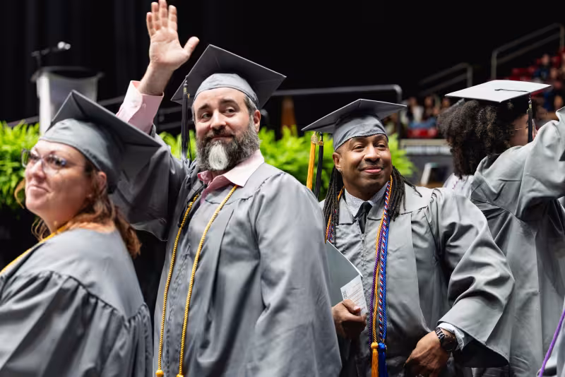 Graduating students waving to family in the crowd