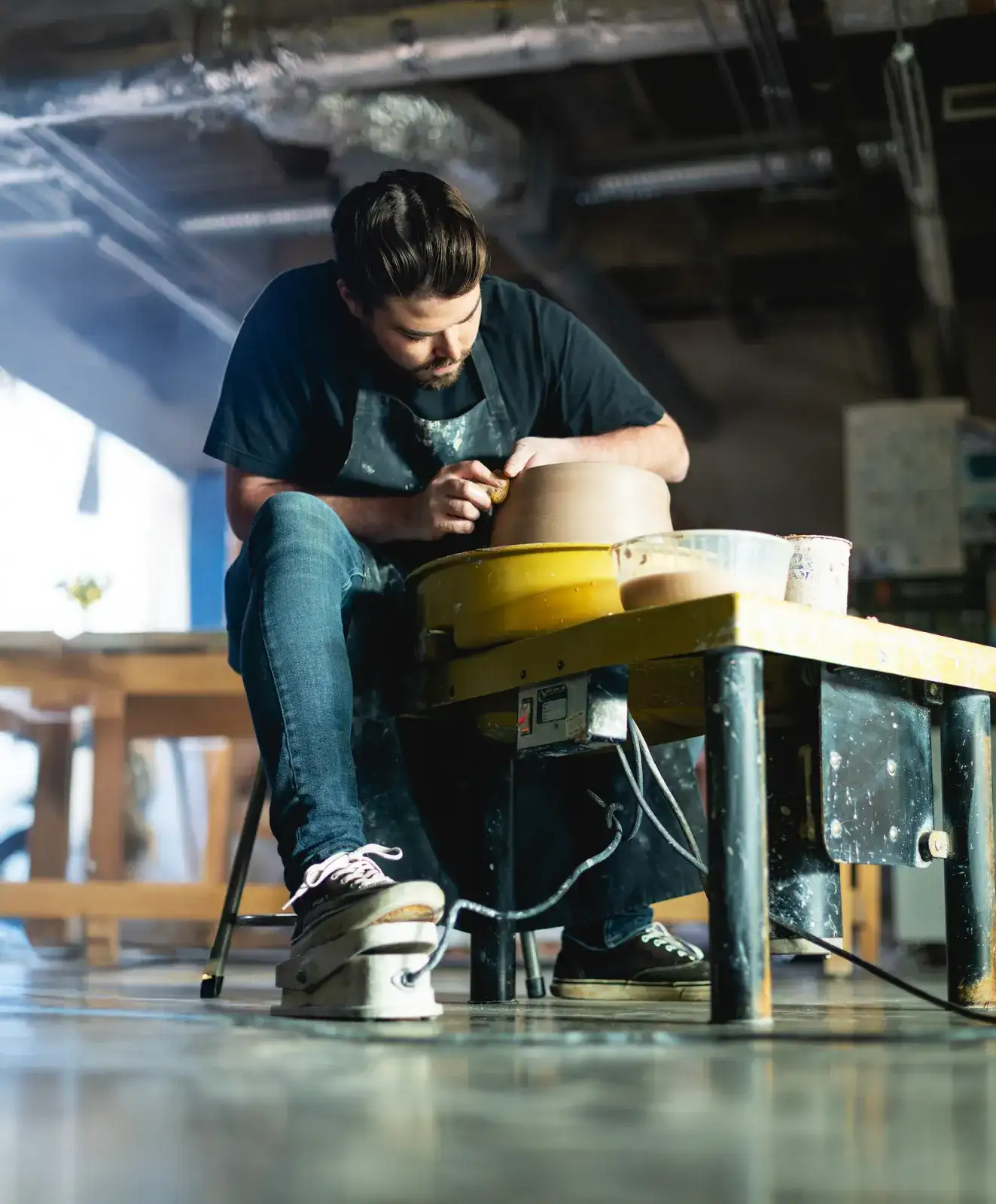 Central Piedmont student concentrating hard while working on clay at pottery wheel in studio.