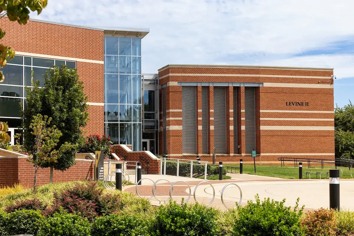 Exterior of large brick Levine Campus building on Central Piedmont’s campus with grounds and walkway in foreground.