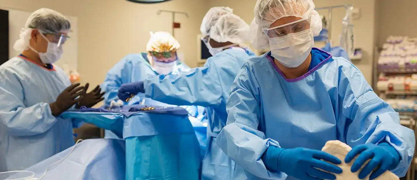 Surgical technology students in full protective gear around an operating table