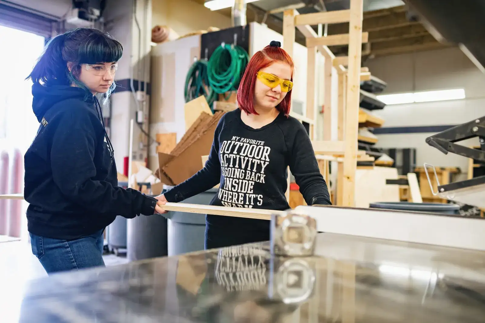 Two students working with timber in a campus workshop