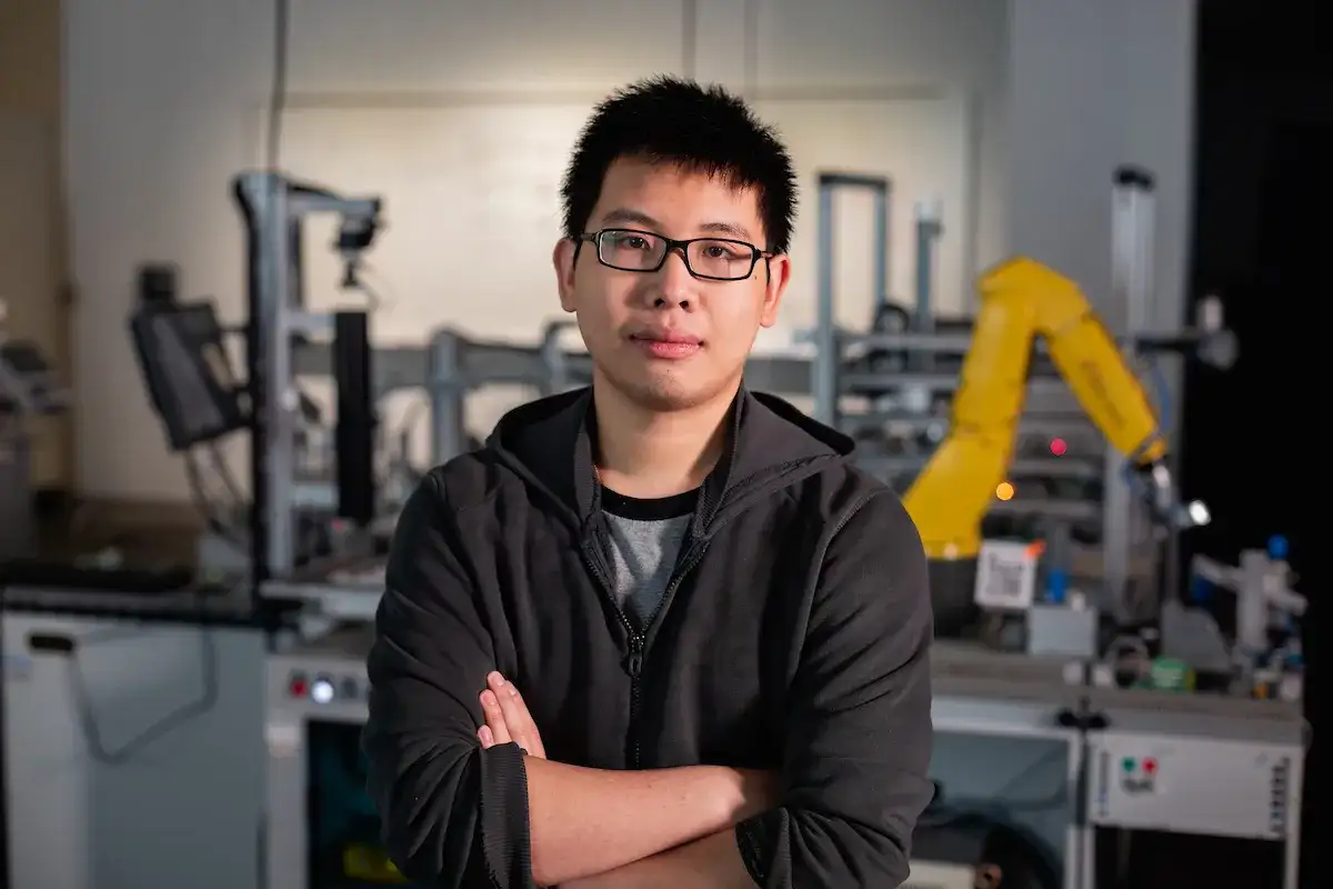 student standing with arms crossed in a mechatronics engineering lab
