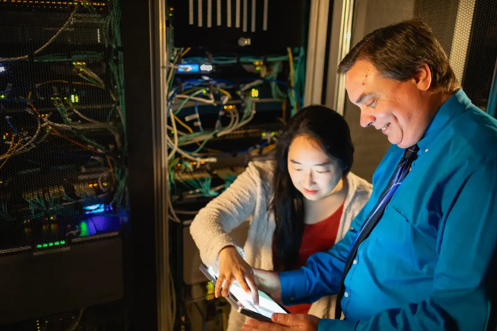 Instructor and student inspecting cabling inside a server rack
