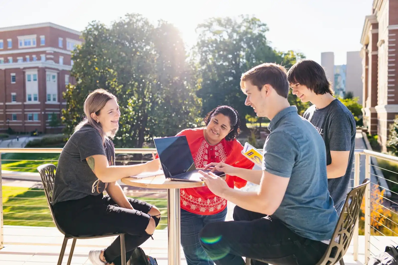 Students working together at an outdoor table on a sunny campus